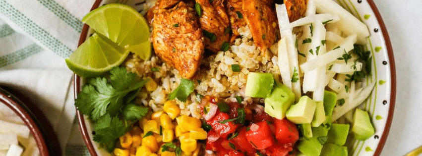 Bowl de poulet grillé avec quinoa, avocat, maïs et légumes frais.