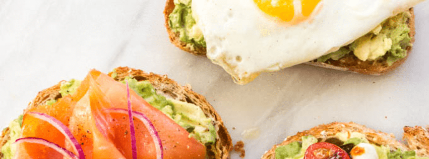 Toasts à l’avocat avec œuf au plat, saumon fumé et légumes frais.