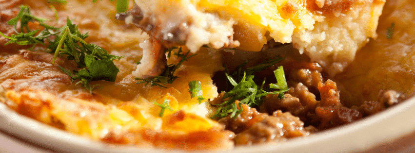 Parmentier de confit de canard avec purée gratinée et viande effilochée en gros plan.